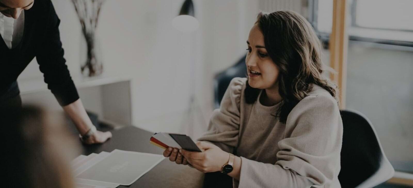 Mitarbeiterin der Markenagentur WHITEVISION sitzt in stylischer Agentur und h&auml;lt Farbpaletten in der Hand, um die Corporate Design Farben f&uuml;r eine Praxismarke auszusuchen