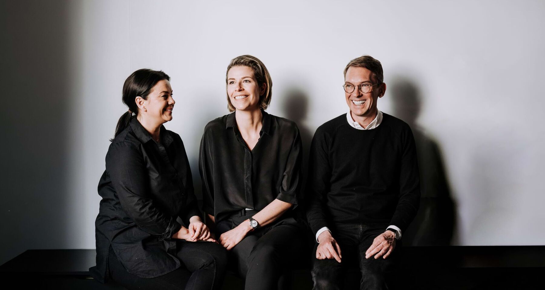 Patricia Schneider, Rabea Hahn und Jens Lichte &ndash; Gesellschafter der Agentur f&uuml;r Praxis- und Klinikmarketing WHITEVISION sitzen nebeneinander und lachen in die Kamera