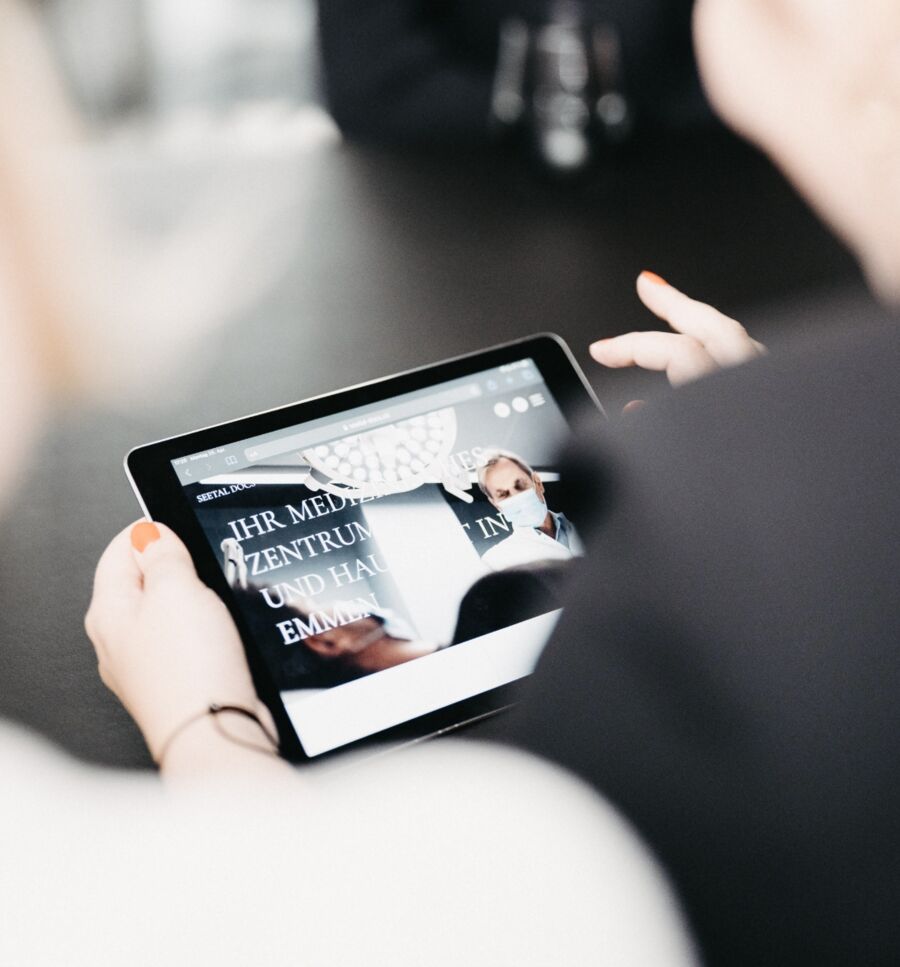 Ein Blick &uuml;ber die Schulter, einer Person, die auf dem Tablet eine Internetseite ansieht.